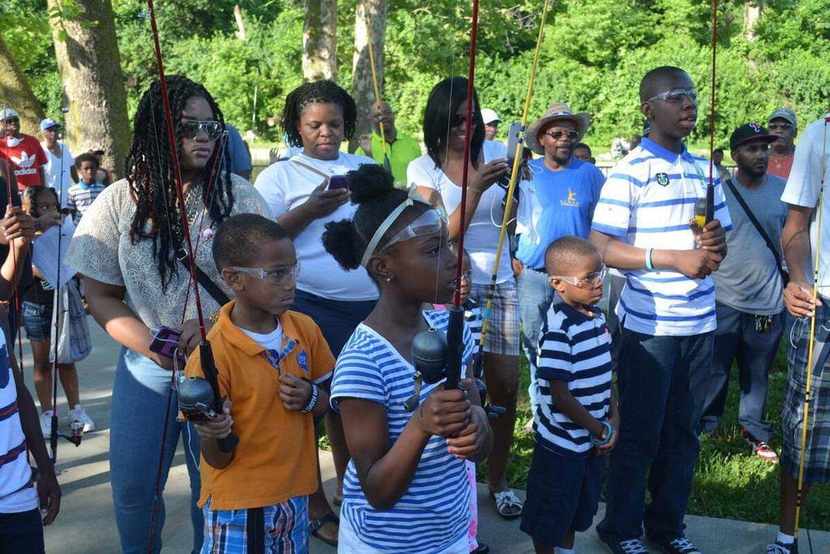 Families listened as organizers of the Urban Kids Fishing Derby gave instructions before the fishing started.