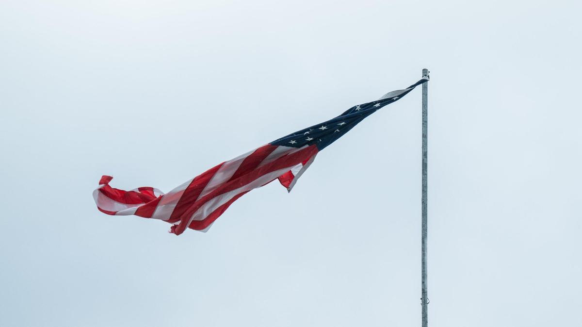 A flag hanging by a thread whips in the wind in Kansas City on Wednesday. Kansas City faced snow and gale force wind gusts overnight and into the morning.