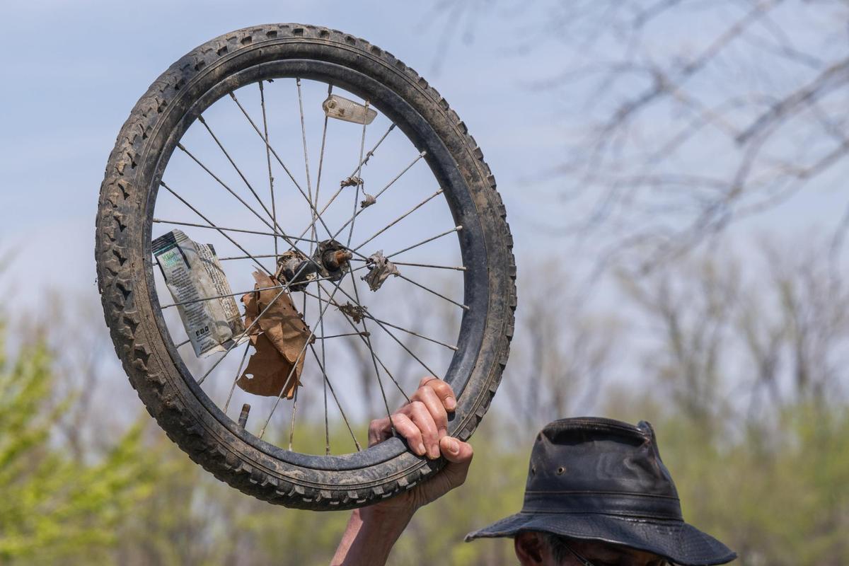 A volunteer held up a bicycle wheel found during Saturday’s cleanup event.