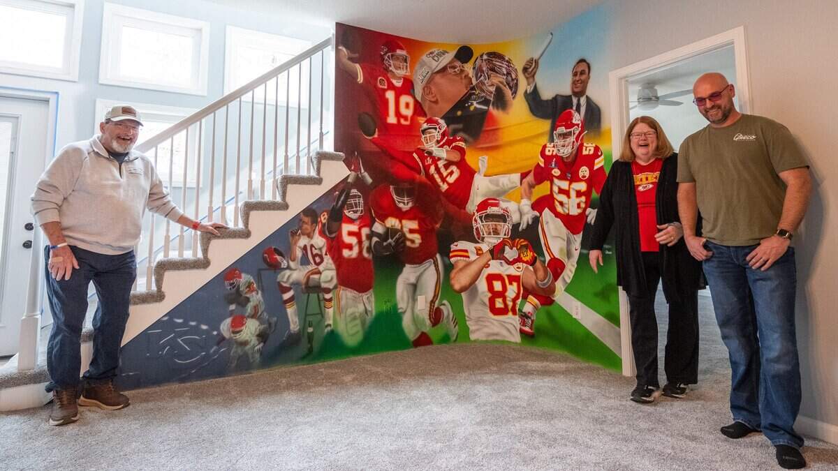 Ed and Mary Ellen Hughes and Craig Greco, stand next to a mural of past and present Kansas City Chiefs players, painted in the Hughes' home by Craig Greco, on Wednesday, March 18, 2026, in Liberty.