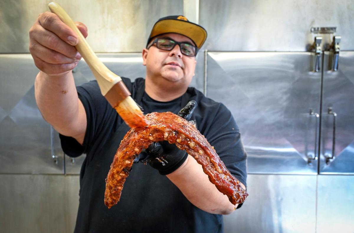 Executive Chef and Pit Master Ted Liberda brushes a sweet chili glaze on a slab of ribs fresh out of the smoker at Buck Tui BBQ, a Thai Kansas City barbecue restaurant he has opened in the space once occupied by Plowboys Barbeque, 6737 W. 75th St. in Overland Park. The Duroc St. Louis style pork ribs feature heavenly BBQ seasoning, Sweet Chili Glaze, served with seasoned jasmine rice, house pickles, Tiger Cry Sauce and Buck Tui BBQ Sauce.