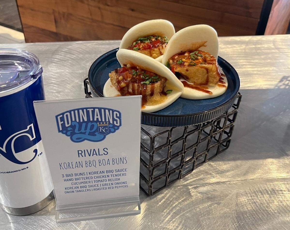 Korean BBQ Bao Buns: hand-battered chicken tenders, Korean barbecue sauce, cucumber, tomato relish, onion tanglers and roasted red peppers served inside a bao bun. This is found at Rivals concession stands inside Kauffman Stadium for 2025.