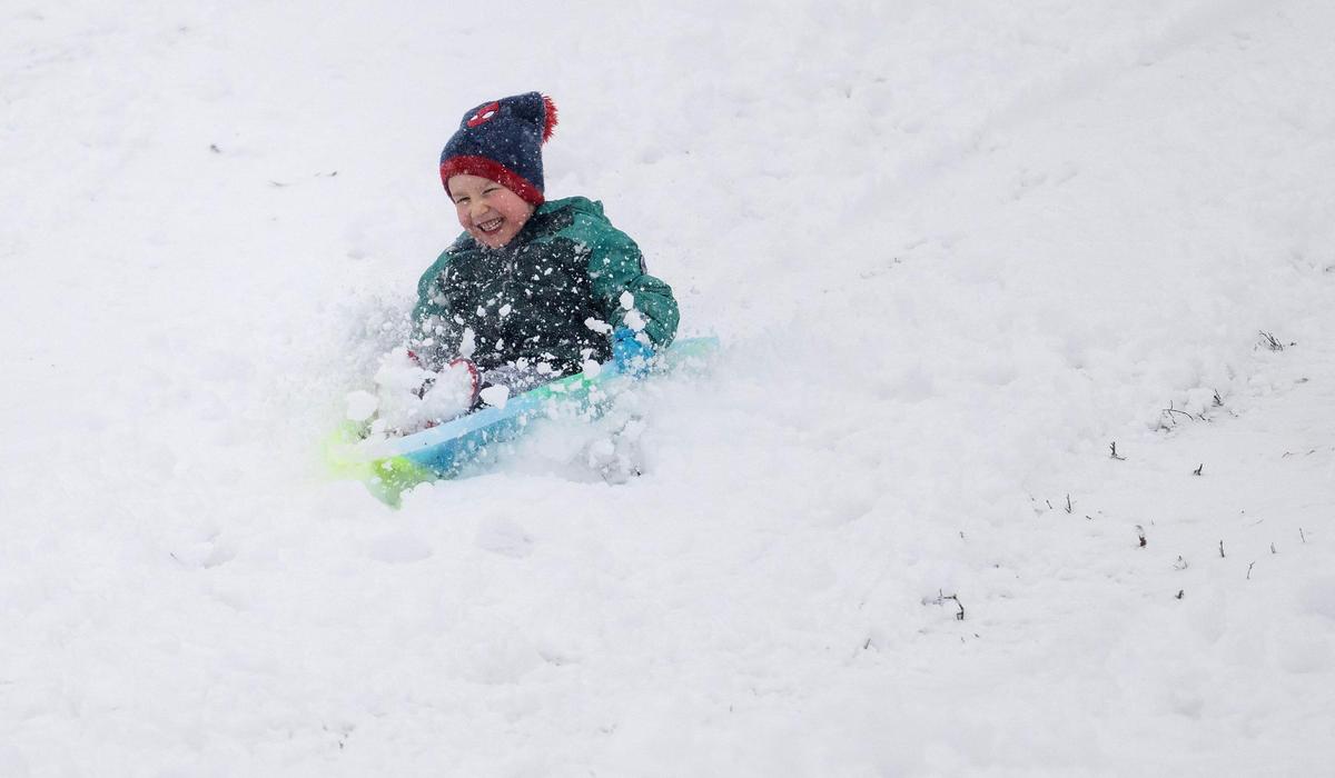 An exuberant young sledder slides down the Brookside Hill on Tuesday, Jan. 9, 2024, in Kansas City after the area was blanketed with a fresh coating of snow.