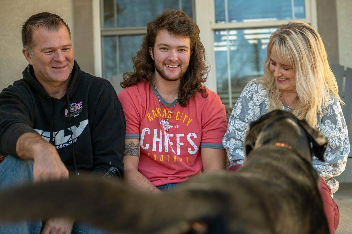 R.J. Appleberry, center, his father Rob and his mother Rachelle sit outside their front porch with their dog Cooper at their home in Blue Springs. Appleberry’s lawsuit against the Blue Springs School District drew attention from across the country.