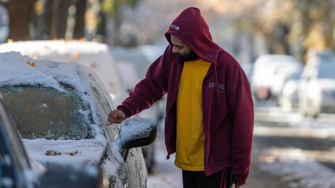 A commuter uses a plastic card to scrape ice off their car window following Kansas City’s first snowfall of the season on Sunday, Nov. 26, 2023.