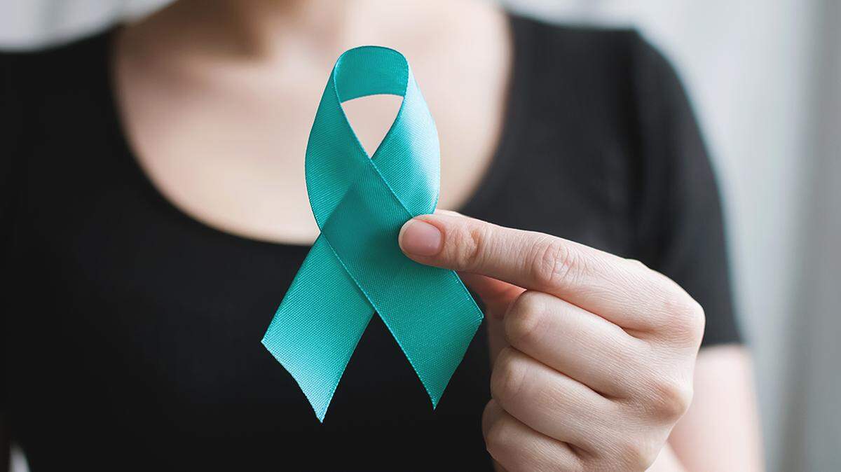 Woman holds in his hand Teal ribbon. Symbolic for cervical cancer, ovarian cancer, gynecological cancer and PCOS. sexual assault awareness month. Women's health care 