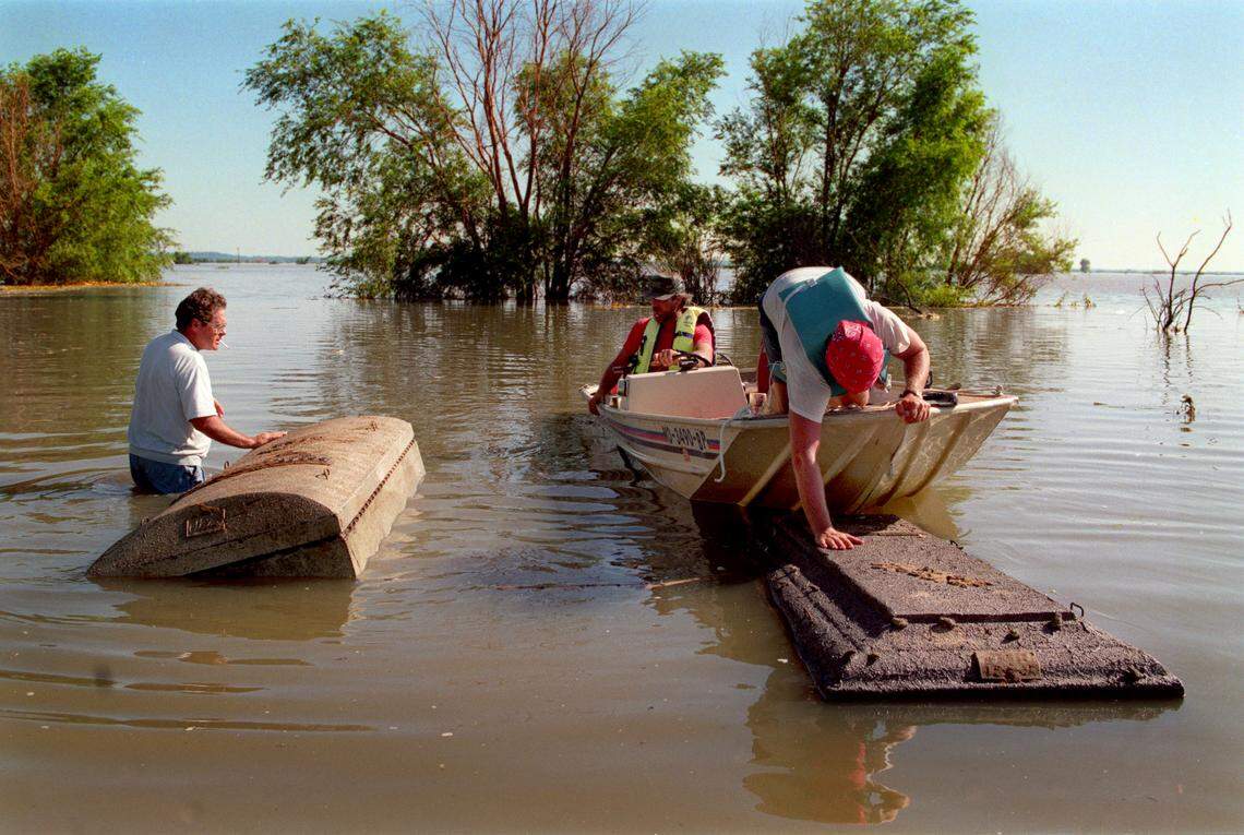 In Hardin, Mo., floodwaters unearthed coffins. Dean Snow (left), who was Ray County coroner at the time, and others tried to move burial vaults toward shallow water after retrieving them from flooded fields.