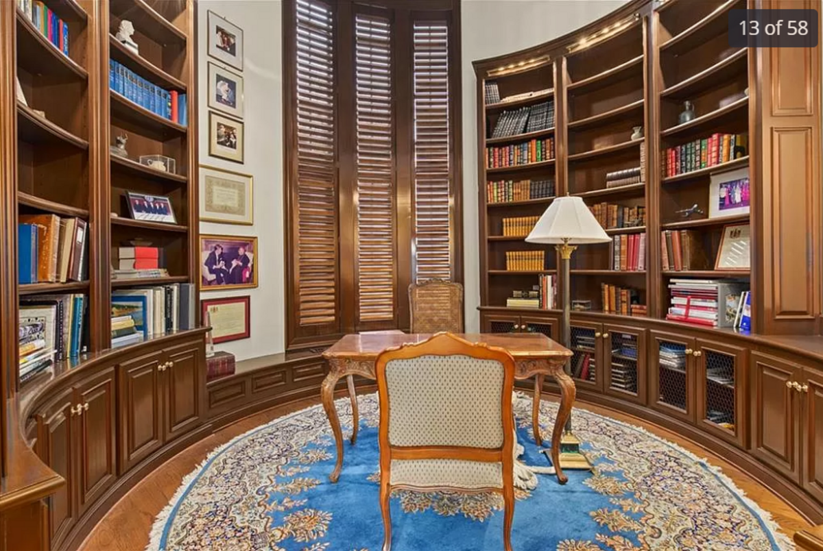 The circular study featuring curved wooden library shelves inside a castle-like turret of the home for sale at 11409 Meadow Lane in Leawood is seen in this listing photo.