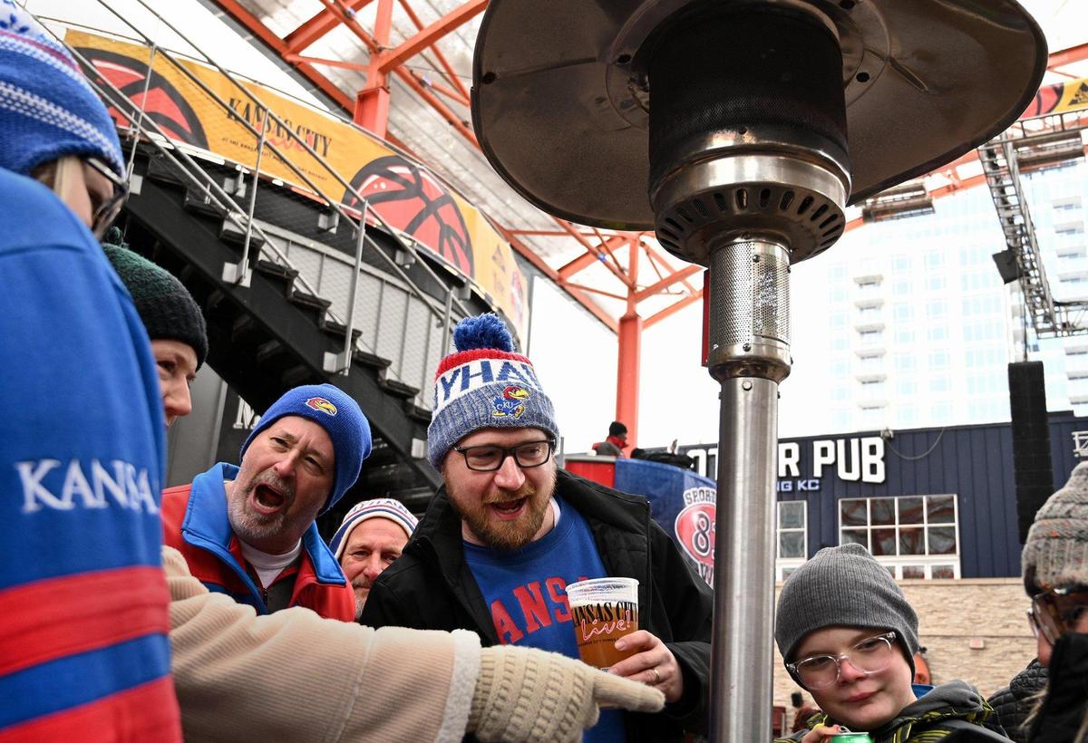 Under the warmth of a heater, Eddie Colbert, of Kansas City, center, hangs out with family and friends in the Power & Light District before the start of the Kansas and West Virginia game of the Big 12 tournament at the T-Mobile Center Thursday, Mar. 10, 2022.