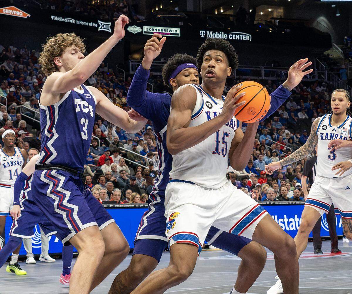 Kansas Jayhawks forward Bryson Tiller (15) is defended by TCU Horned Frogs guard Liutauras Lelevicius (3) and forward Micah Robinson (5) during the second half of a Big 12 Tournament game at T-Mobile Center on Thursday, March 12, 2026, in Kansas City.