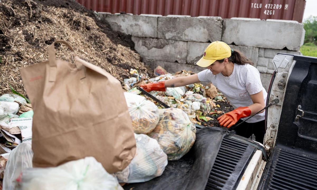 Romi Shaw empties customers’ food waste into a pile as part of their work for Compost Collective KC in May, 2023. The operation hauls food waste from more than 3,000 households back to Urbavore, where a composting facility turns what would otherwise be landfill-destined trash into nutrient-rich soil.