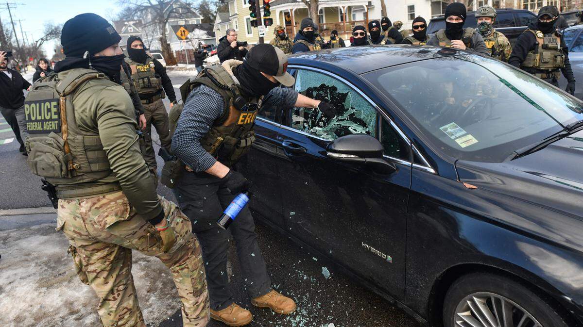 ICE and other federal officers break a car window as they remove a woman from her vehicle in Minneapolis on Jan. 13.