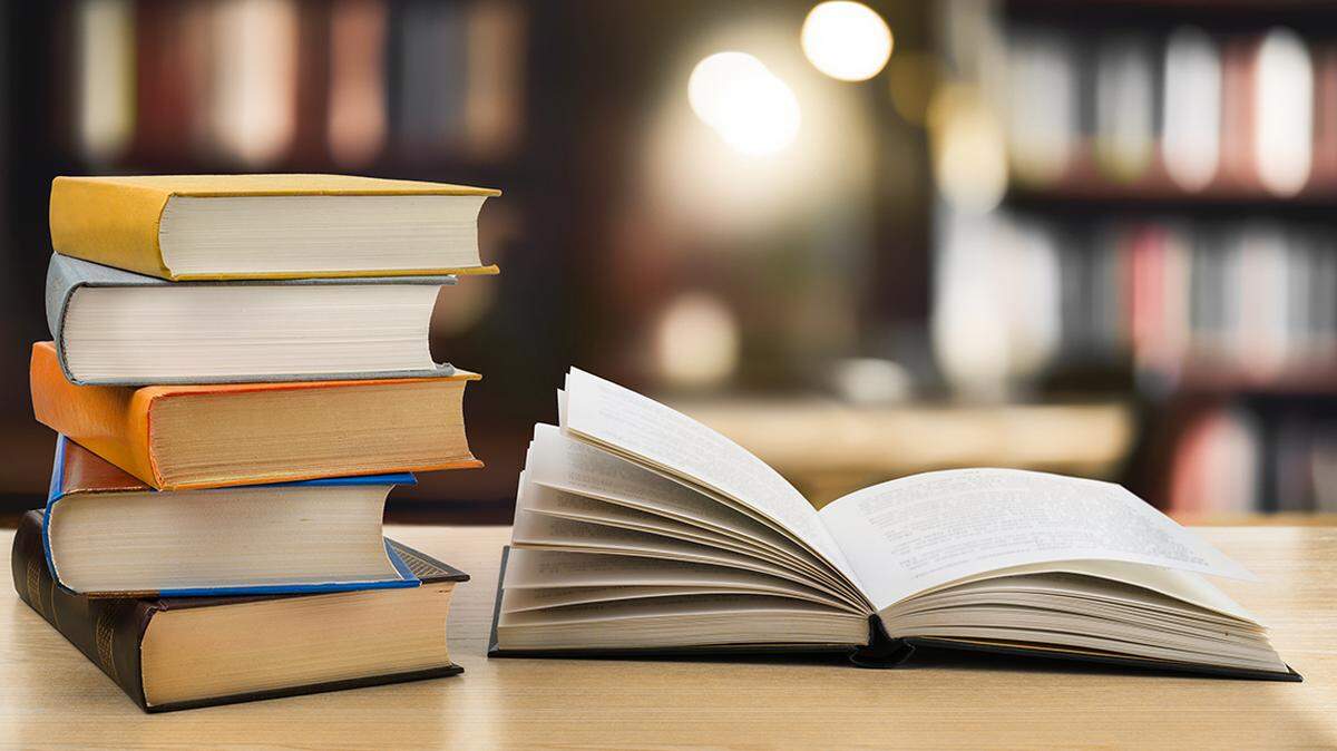 Book stack and open book on the desk in public library