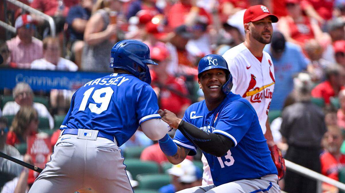 Playing DH Monday in St. Louis, Salvador Perez, center, is helped up by Royals teammate Michael Massey after scoring from first on a triple by right fielder MJ Melendez during the fifth inning at Busch Stadium.