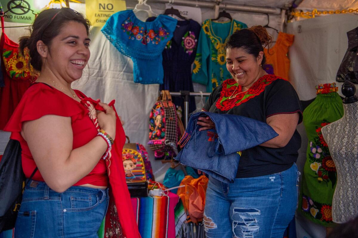 Yanelle Rodriguez, right, helps Maria Ramirez find a fitted dress while shopping through booths during the Cinco de Mayo celebration at Guadalupe Centers on Friday, May 5, 2023, in Kansas City.
