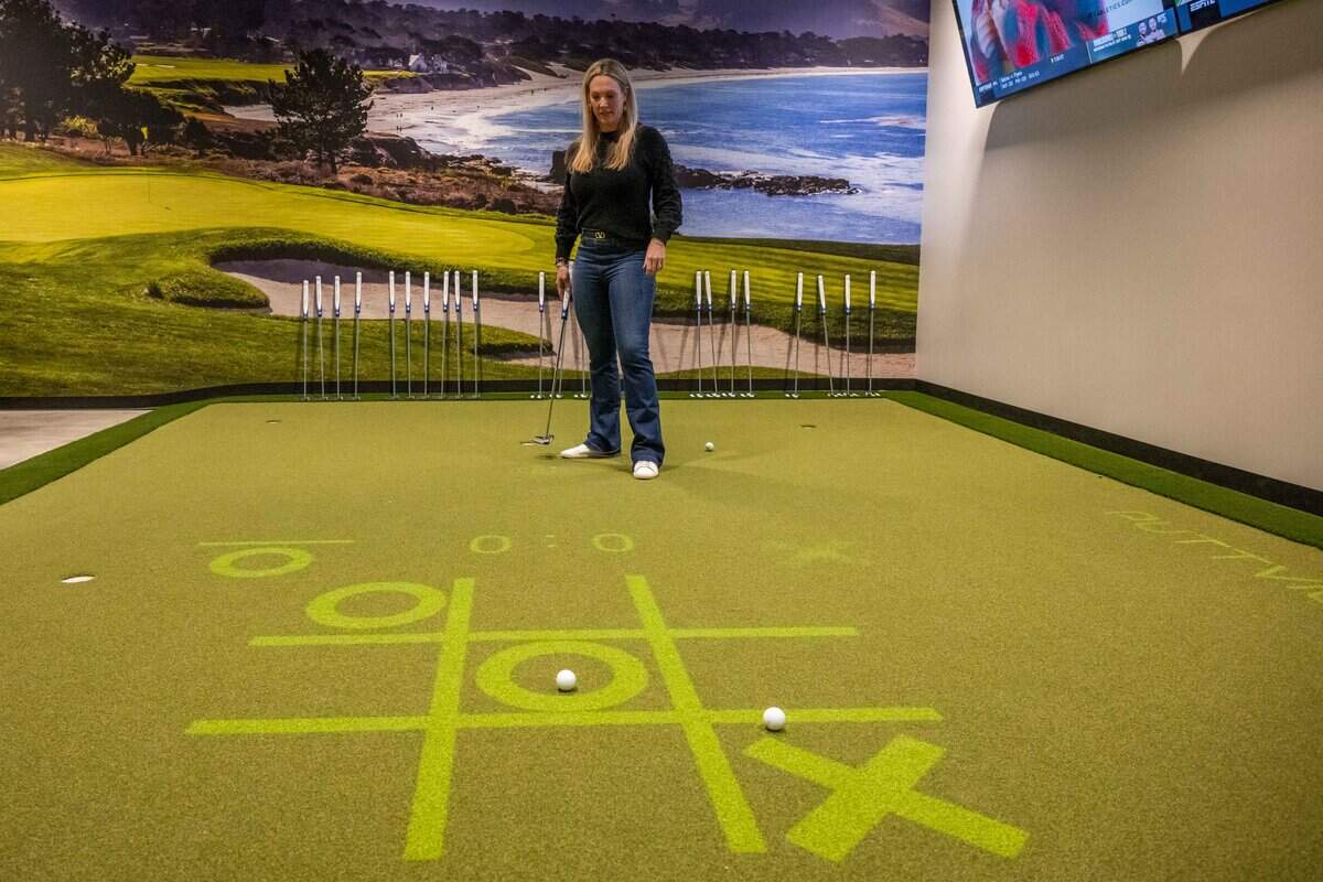 CMO Lauren Cody demonstrates a golf simulator game in a private room at Tap-Ins at the Greenhouse, a new restaurant/mini golf concept in Overland Park, on Wednesday, December 3, 2025.