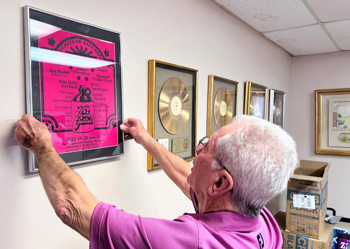 Ozark Music Festival promoter Chris Fritz hangs up a poster in his office advertising the 1974 event in Sedalia.