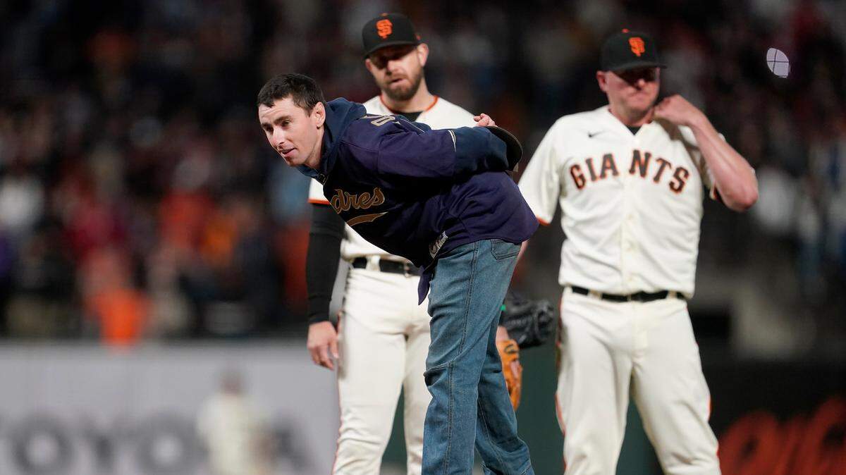 A fan stands on the mound in front of San Francisco Giants third baseman Evan Longoria, left, and pitcher Jake McGee during the ninth inning of a baseball game between the Giants and the New York Mets in San Francisco, Monday, Aug. 16, 2021. (AP Photo/Jeff Chiu)