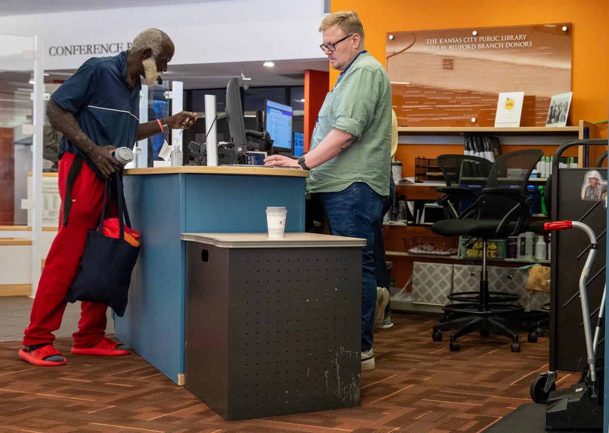Sean Collins, right, Patron Safety Engagement Ambassador at the Lucile H. Bluford Branch of the Kansas City Public Library, helps a library patron on Wednesday, Sept. 18, 2024. Peer navigators can refer those in need to University Behavioral Health for services.