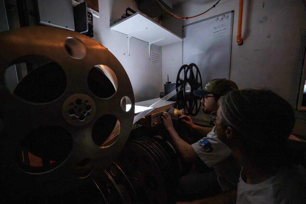 Jakob Roberts, left, general manager of Screenland Armour Theatre, and projectionist Ethan Foster thread a 70mm reel during a screening of “Sinners” on Friday, March 27, 2026, in North Kansas City.