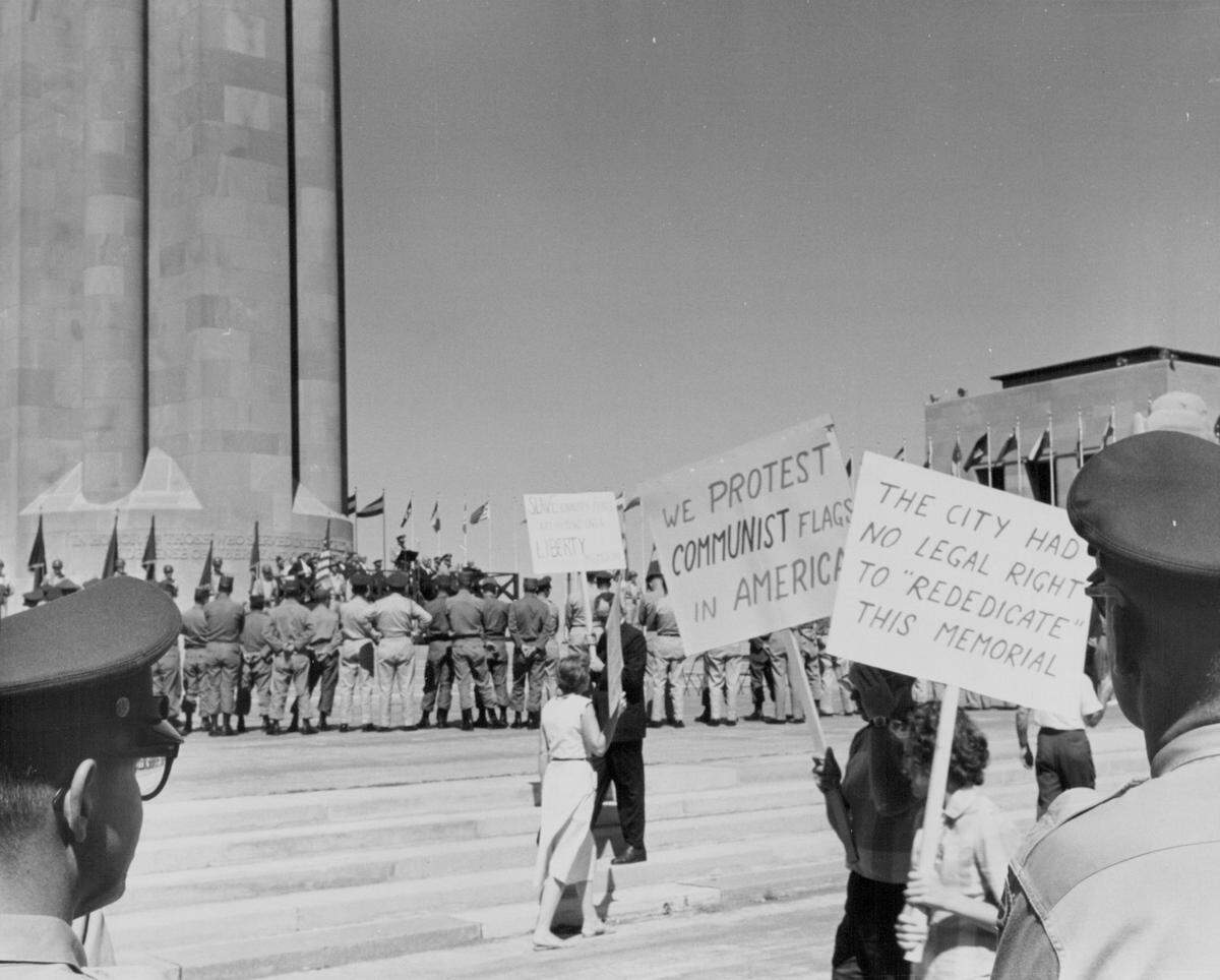 Protesters demonstrate at Liberty Memorial while a military division celebrates its 35th anniversary in 1962.