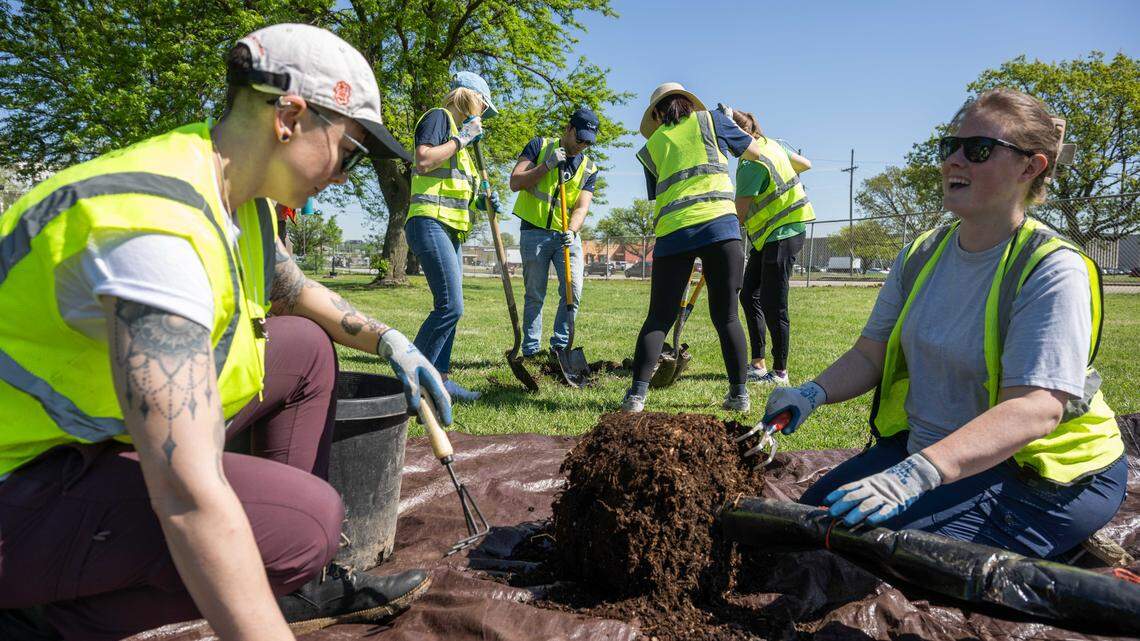 Volunteers dig a hole and prep tree roots for planting during a tree planting event on Thursday, April 16, 2026, in Kansas City.