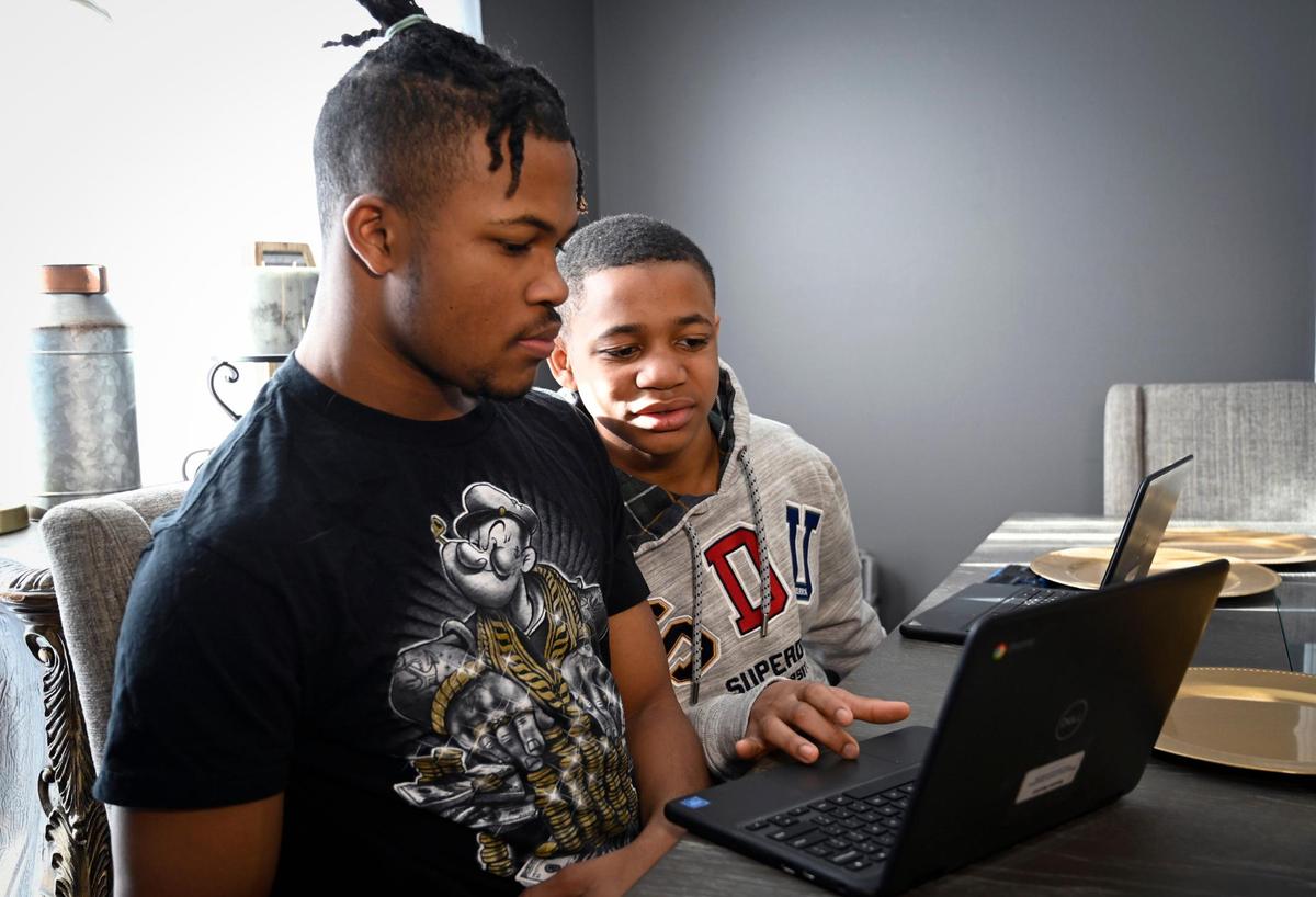 Brandon Marshall, 15, left, a freshman at Lee’s Summit North High School, and his brother Erza, 10, a fifth-grader at Richardson Elementary School, look over some school work at their home. Their mother Davoya has been involved in school district affairs at a time when controversy has roiled districts across the Kansas City area.