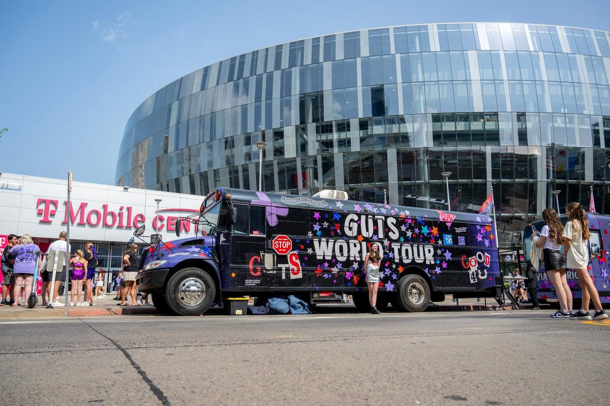 Fans of Olivia Rodrigo take photos by a Guts World Tour-themed school bus on Friday while waiting for her Kansas City concert.