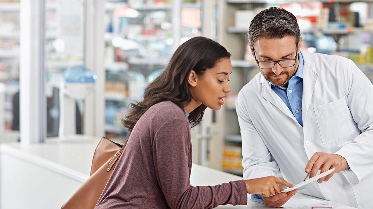 Shot of a male pharmacist assisting a customer at the prescription counter. All products have been altered to be void of copyright infringements