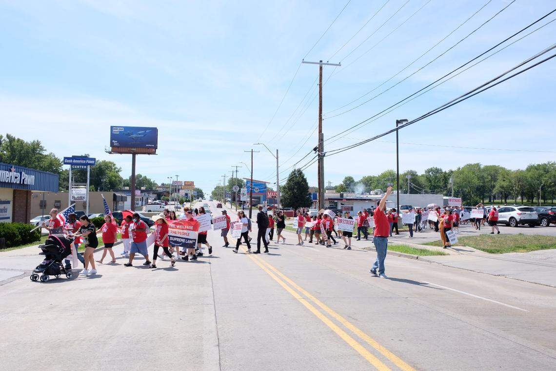 Activists with groups including Stand Up KC cross Wornall Road before joining workers at a Taco Bell who walked off the job and shut down the store Thursday.