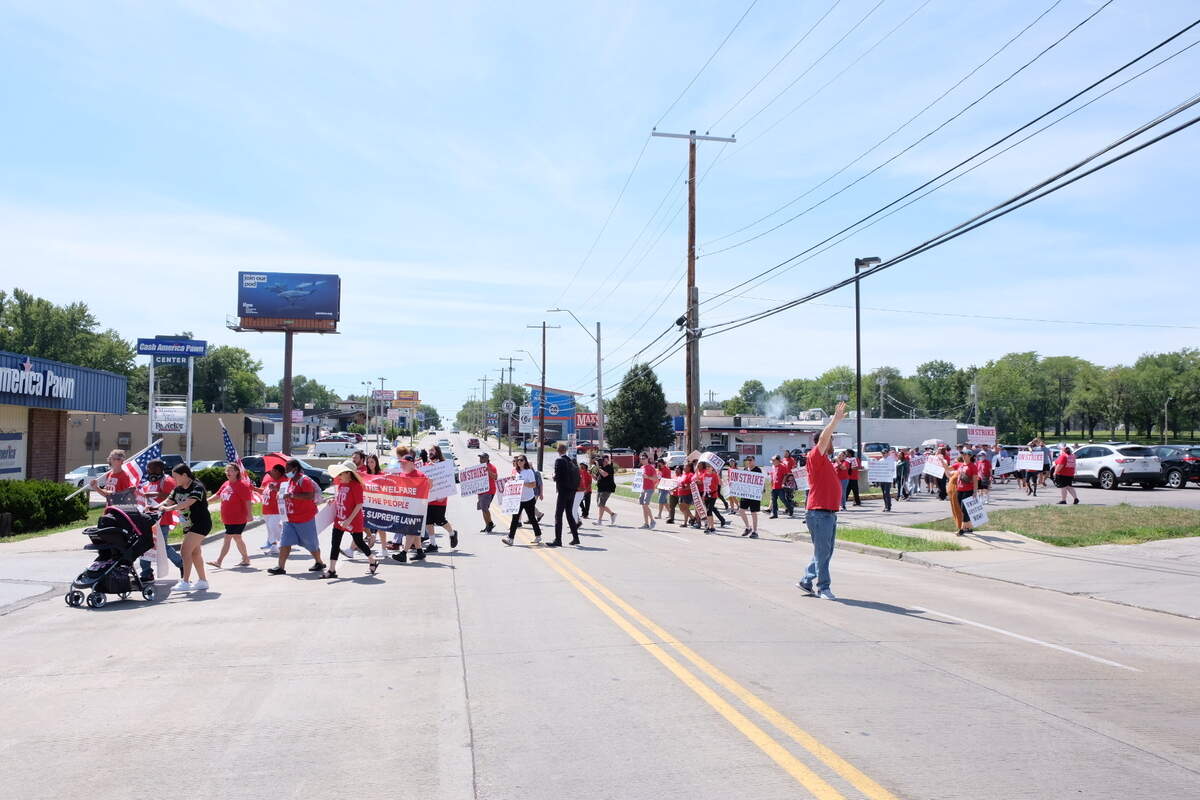 Activists with groups including Stand Up KC cross Wornall Road before joining workers at a Taco Bell who walked off the job and shut down the store Thursday.