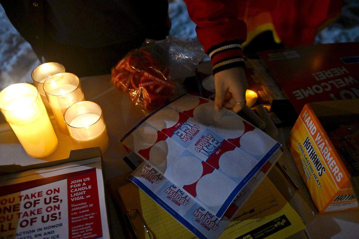 People gather items from a table during a candlelight vigil outside Research Medical Center to honor Alex Pretti on Thursday, Jan. 29, 2026, in Kansas City.