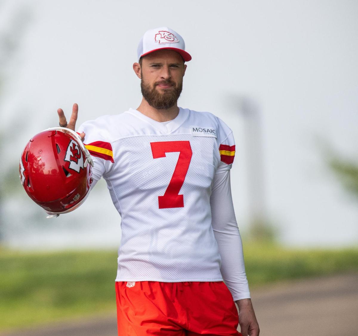 Kansas City Chiefs kicker Harrison Butker (7) flashes a peace sign to fans while walking to the field during training camp on Monday, July 22, 2024, in St. Joseph.