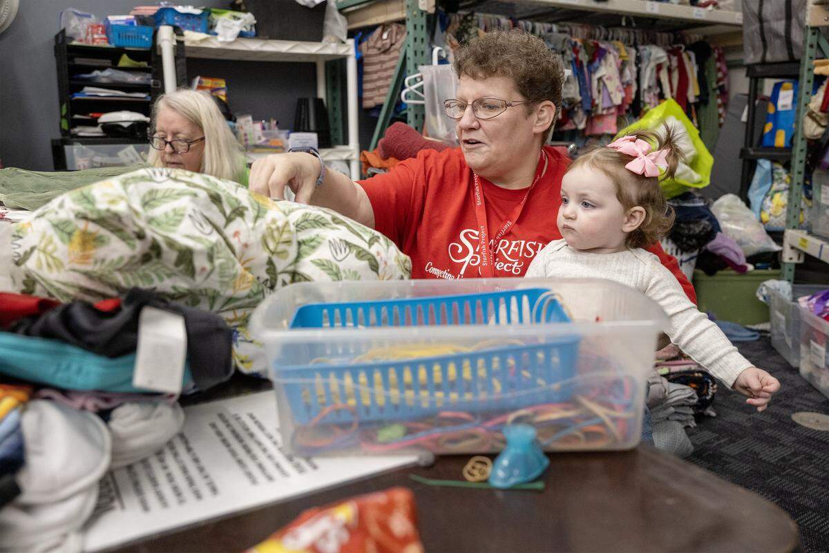 Kelly Patterson, volunteer coordinator for the Starfish Project, organizes donations with her 14-month-old granddaughter Lilah, on Thursday, Feb. 12, 2026, in Olathe. The Starfish Project is a nonprofit that provides essential items free of charge to those in need. The organization has recently received notice that it must relocate. Patterson said her volunteers restock the entire store three times a day.