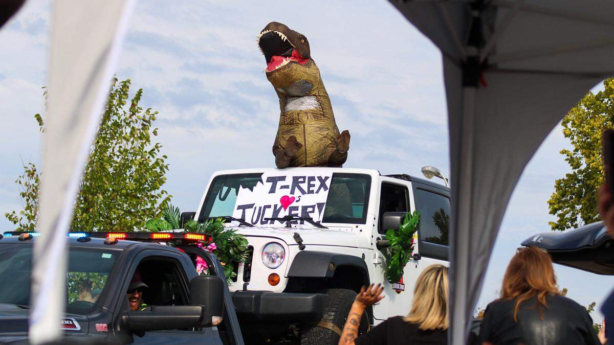 A person in a T-Rex costume participates in a parade for Tucker Langford, a 3-year-old battling terminal illness, on Saturday, Oct. 11, 2025.