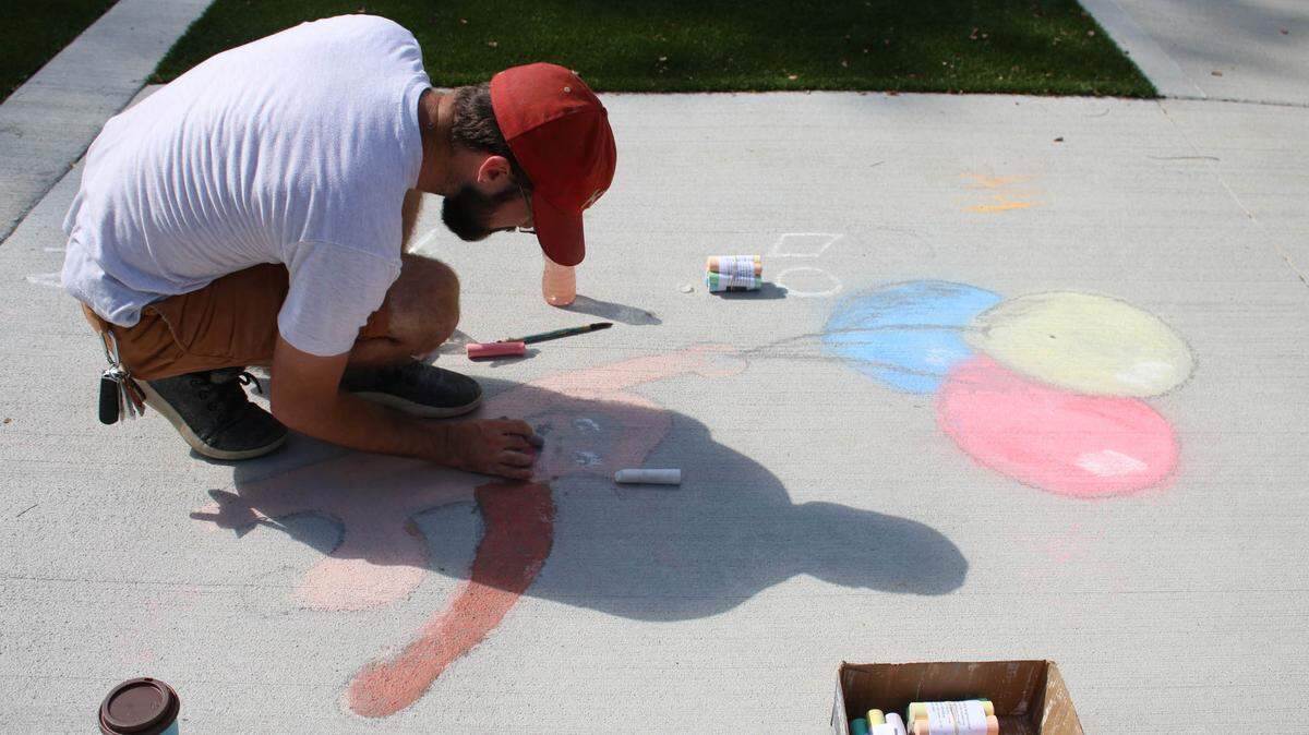 Chris Moll works on his drawing of Curious George Aug. 21 at Cherokee Park. He hoped to encourage kids to make their own drawings for Chalk the Walk.