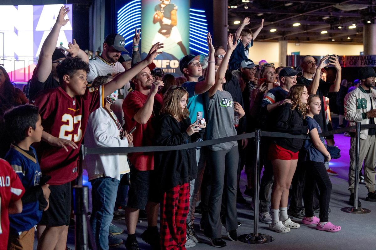 Fans try to get in the frame of a live television stream at the NFL’s Super Bowl Experience on Thursday, Feb. 9, 2023, in Phoenix.