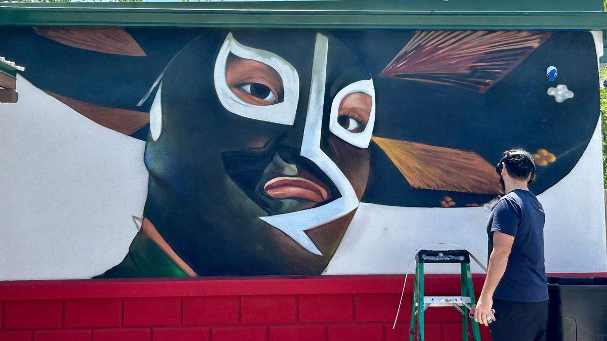 Isaac Tapia paints the side of El Luchador, a new Mexican restaurant in Gardner.