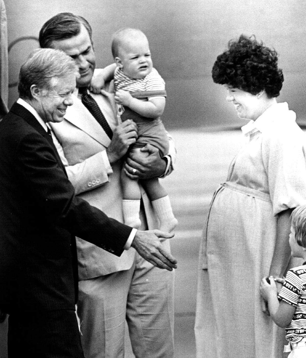 President Jimmy Carter introduces himself to a shy William Teasdale, age 4, as Gov. and Mrs. Joseph Teasdale and infant, John Teasdale, watch at Downtown Airport in Kansas City.
