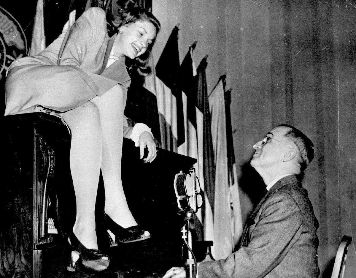 Actress Lauren Bacall poses on the piano as Vice President Harry S. Truman plays during a program for servicemen at the National Press Club canteen in 1945. 