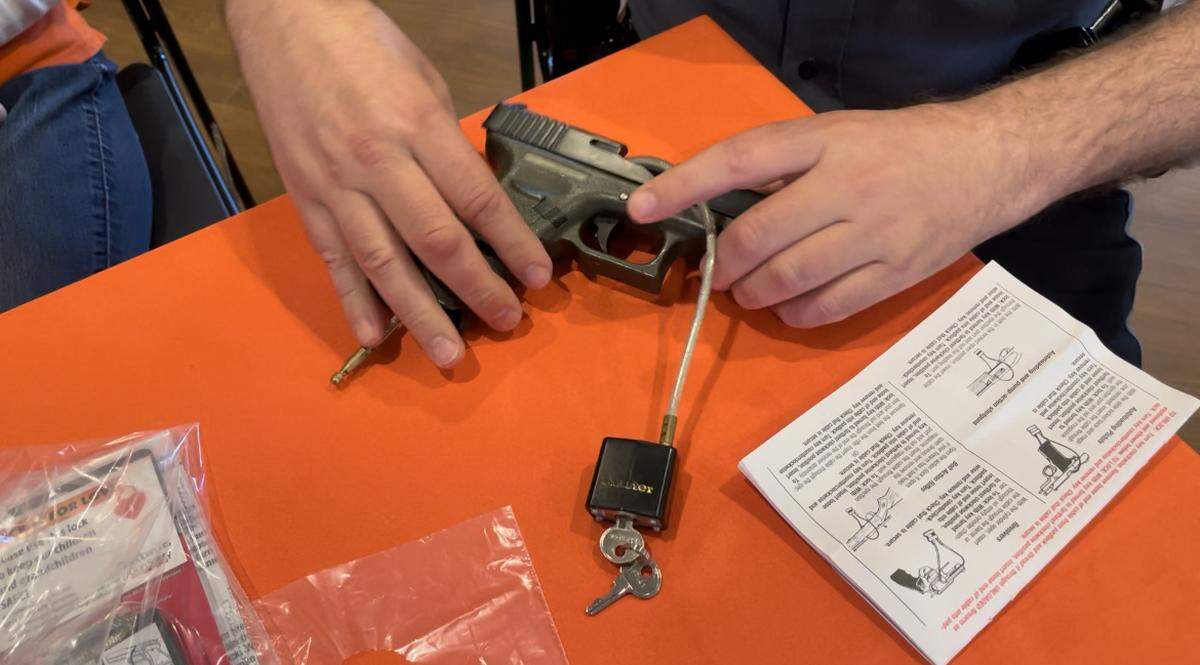 Officer Andy Hamil, a KCPD community police officer, demonstrates how to secure a gun lock on an unloaded gun at Charlie’s House, a Kansas City organization focused on preventing kids from injury and death in the home, on Saturday, April 2. 