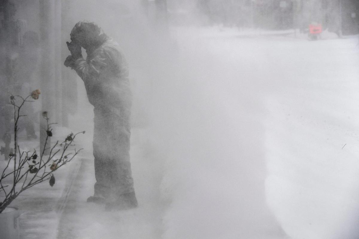 Izzy Licos turns to protect himself from windblown snow while he was clearing a drift from the sidewalk of a business Sunday, Jan. 5, 2025, in downtown Overland Park. Blizzard conditions hit the Kansas City metro crippling transportation and shutting down several businesses.