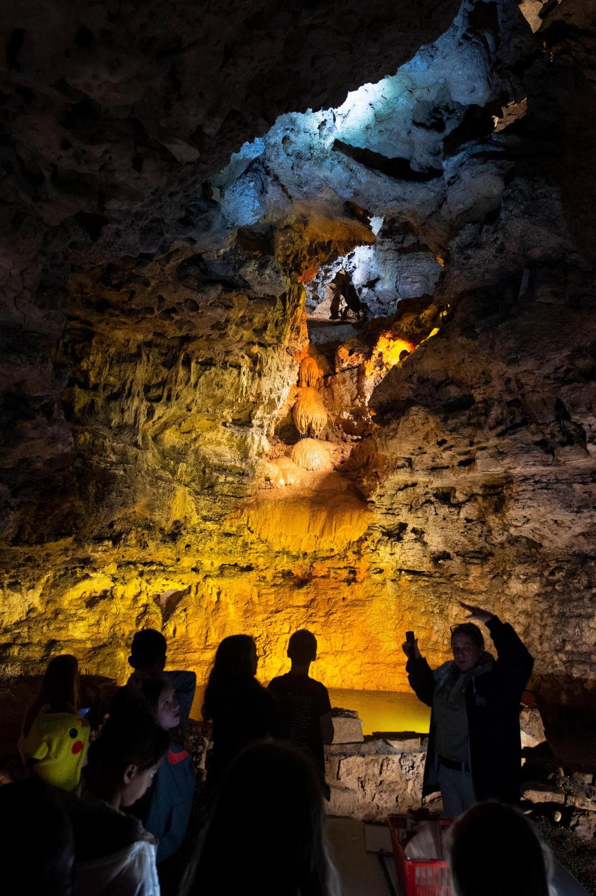 Tour guide Karen Sanders talks to students from Crestview Elementary in North Kansas City as they tour Stark Caverns in Eldon. Behind her is Onyx Falls, a flowstone formation where white calcite is tinted by iron as water makes its way down through the earth.