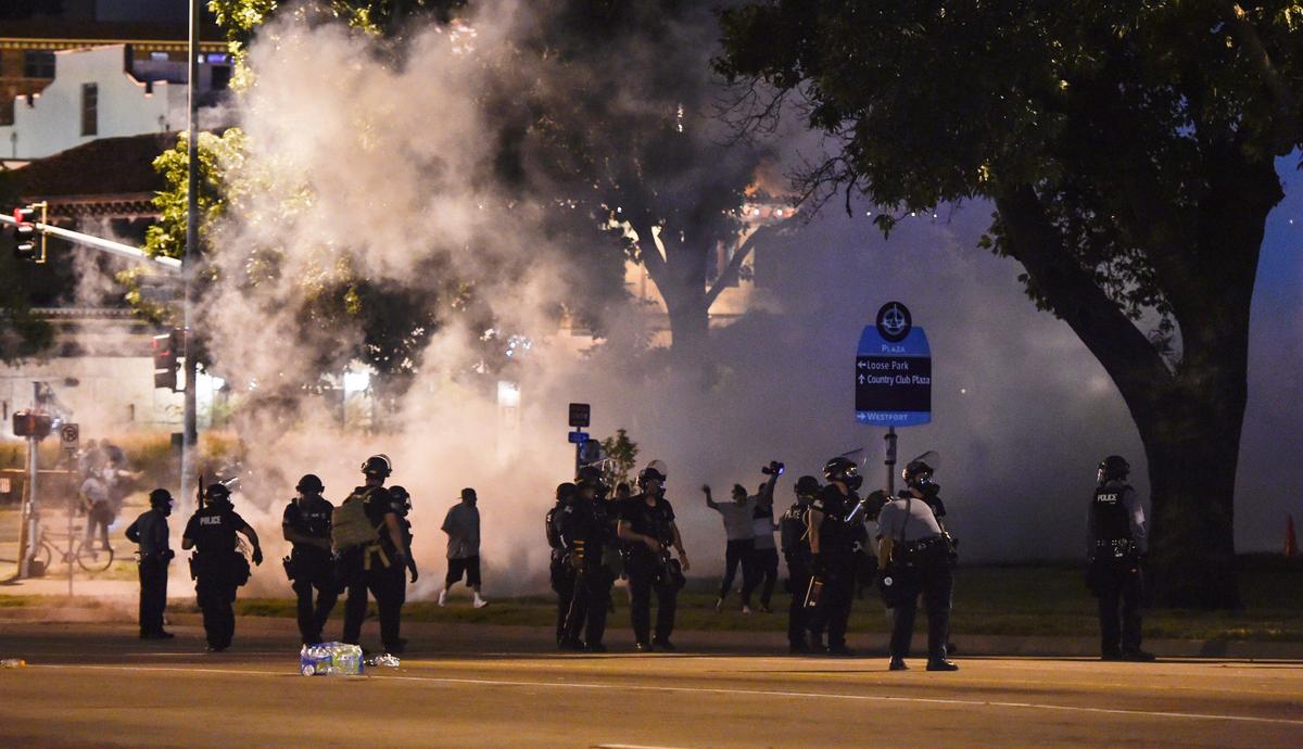 Law enforcement officers deploy tear gas on Main Street near the Country Club Plaza Monday to disperse protesters who continued to protest the death of George Floyd while in the custody of Minneapolis police.