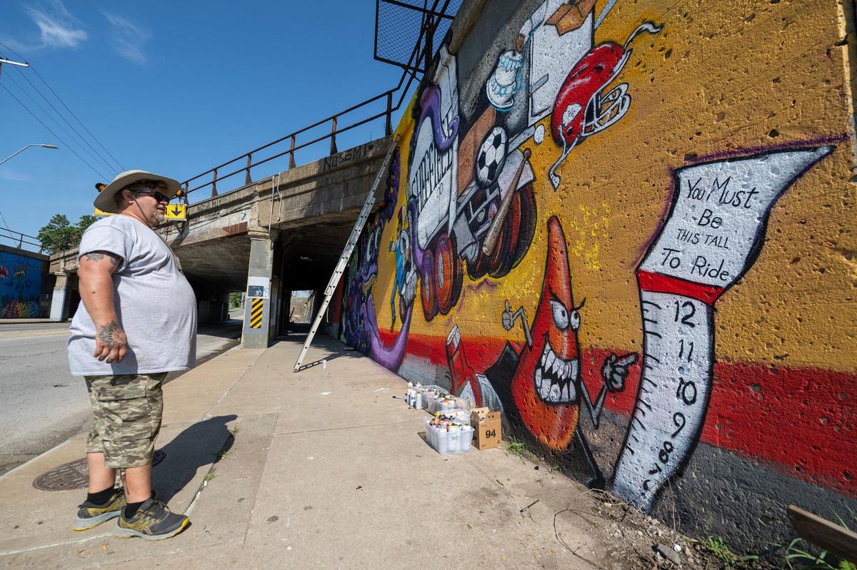 Artist Mike Elder steps back to look over his mural he was painting on the Independence Avenue truck-eating bridge.