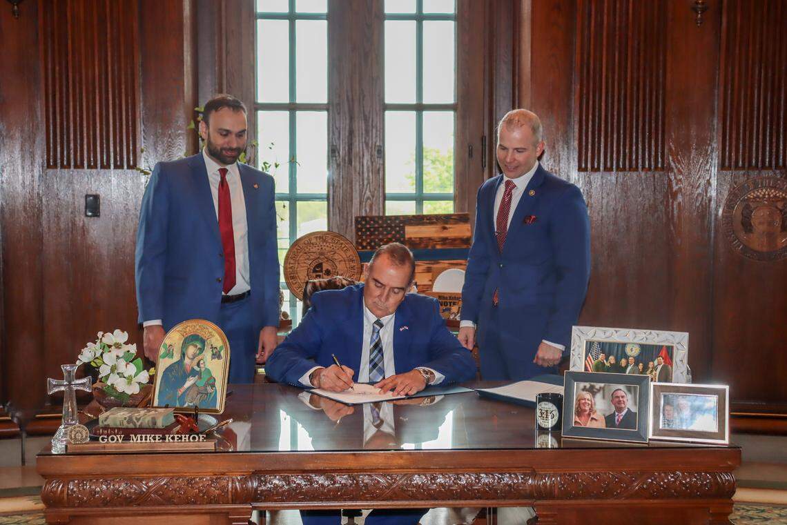 Missouri Gov. Mike Kehoe, center, signs into law legislation that allowed Attorney General Andrew Bailey to immediately appeal a ruling that cleared a path for abortions to resume. Rep. Ben Keathley, a Chesterfield Republican, left, and Sen. Rick Brattin, a Harrisonville Republican, right, stood behind him.