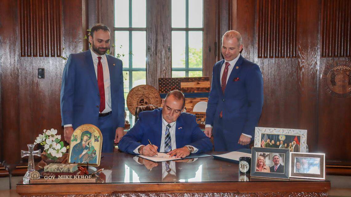 Missouri Gov. Mike Kehoe, center, signs into law legislation that allowed Attorney General Andrew Bailey to immediately appeal a ruling that cleared a path for abortions to resume. Rep. Ben Keathley, a Chesterfield Republican, left, and Sen. Rick Brattin, a Harrisonville Republican, right, stood behind him. 