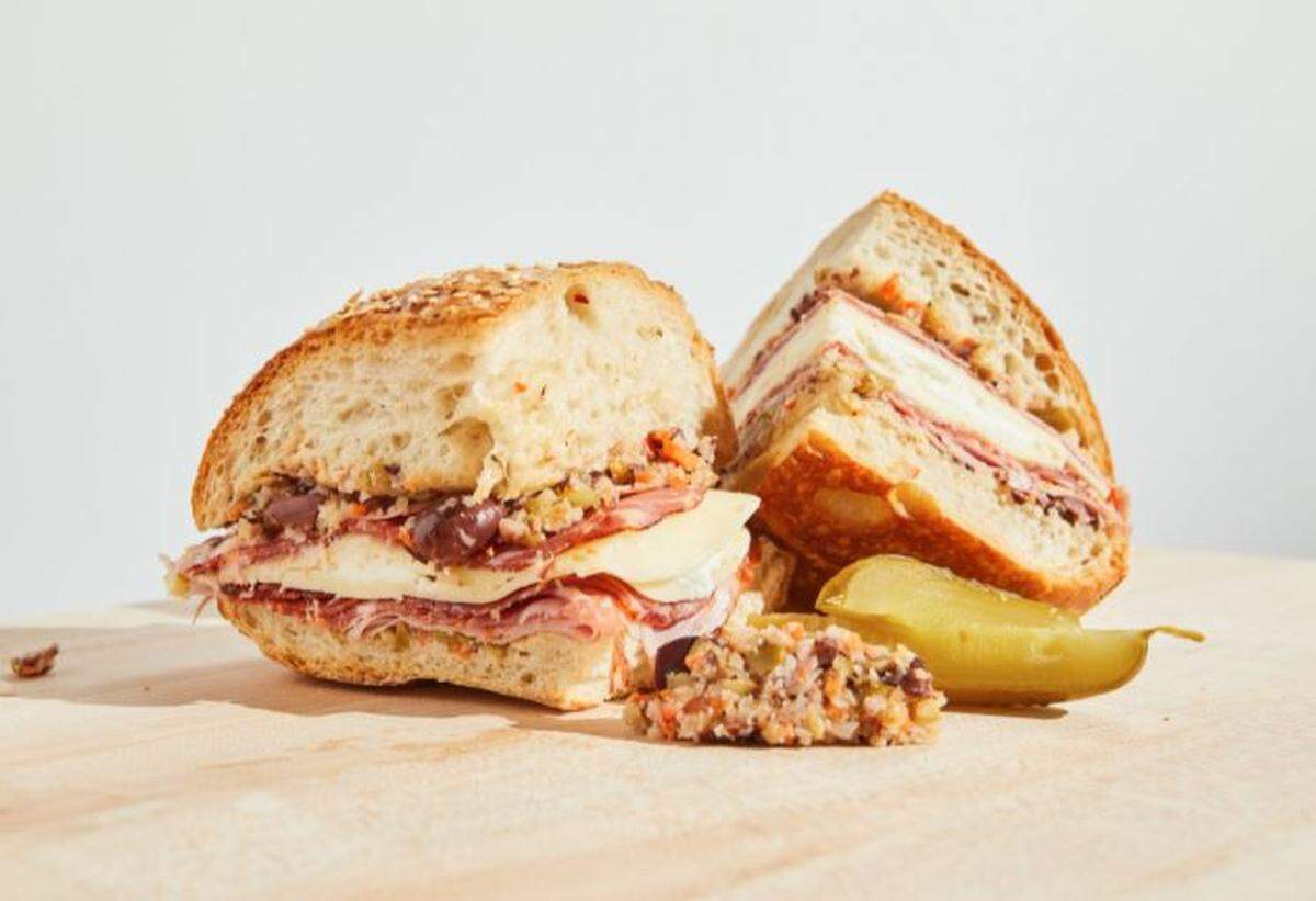 King G’s muffuletta, a Sicilian-style sesame loaf filled with sliced mortadella, soppressata, capicola, provolone, olive salad, giardiniera and mozzarella.