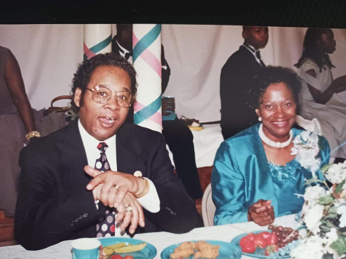 Robert Braynham (left) and his wife, Joanna Braynham (right) smile into the camera at a dinner. They met in church and had five daughters together.