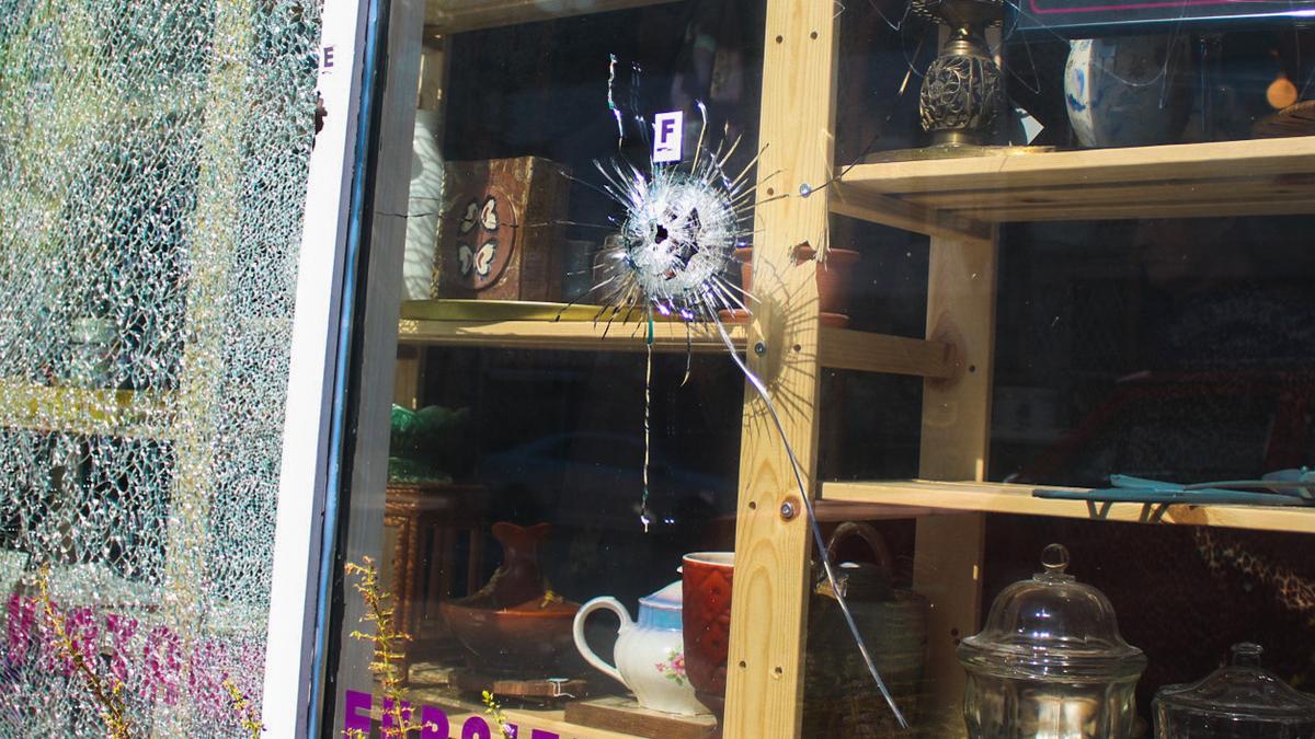 A bullet hole marked with police tape is seen on the front window of Pop! Vintage Furniture and Accessories on Westport Road. Five people were injured in the shooting Wednesday night, police said.